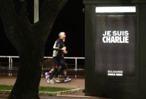 People run by a kiosk with a poster reading I Am Charlie on the Promenade des Anglais in Nice, southeastern France, Jan. 14, 2015.