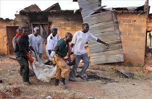 Rescue workers carry the  body of a victim of sectarian violence in Kurujantar, some 19 miles south of Jos, Nigeria, Friday.